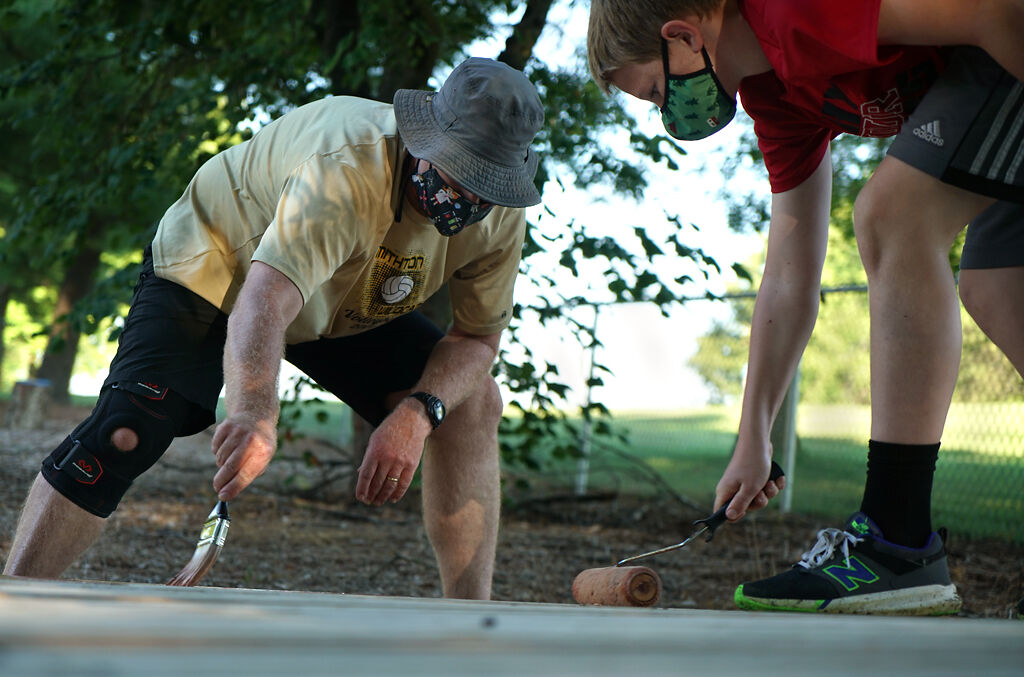 Matt Wightman paints the seesaw with his son on Thursday,